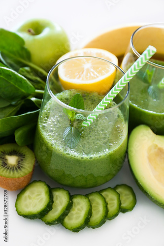 Freshly made green smoothie made of vegetables  fruits  herbs and greens. Glass of blended vegan beverage with ingredients around. Top view  close up  copy space  background.