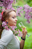 Beautiful female with glass of champagne in the sakura garden
