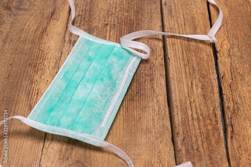 Biohazard, health and medical concept: disposable medical protective mask on a wooden table.