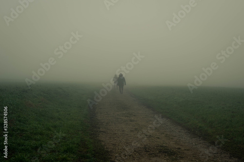 Two people walking down a path with mist. Mysterious and adventurous photo.