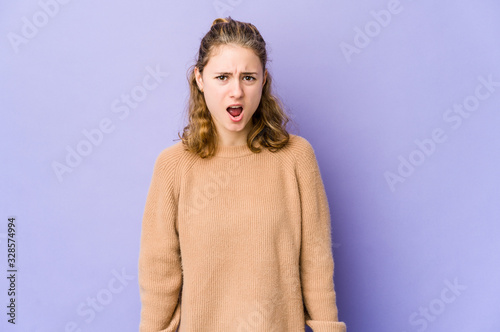 Young caucasian woman on purple background shouting very angry, rage concept, frustrated.