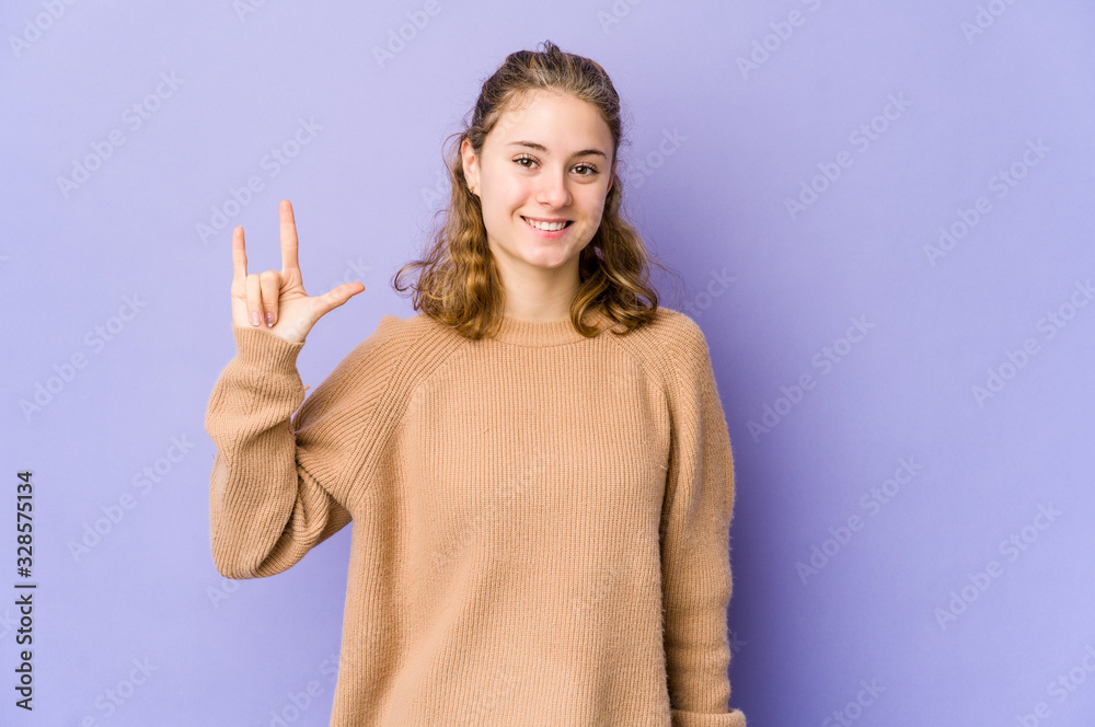 Young caucasian woman on purple background showing a horns gesture as a revolution concept. Young caucasian woman on purple background showing a horns gesture as a revolution concept.