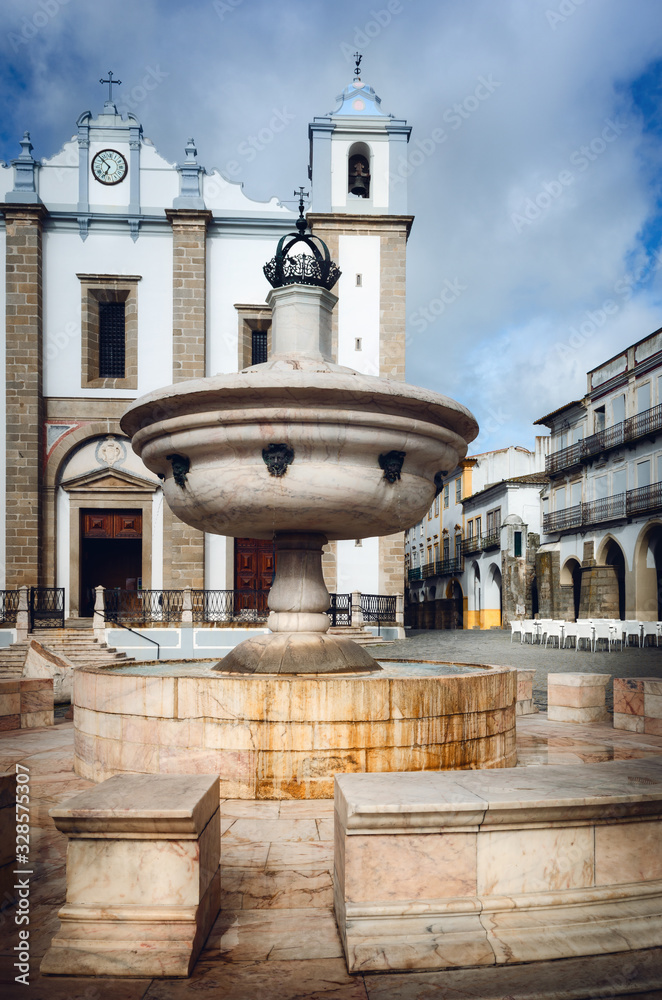 Praca do Giraldo, main square of Evora, city of the Alentejo region in Portugal, famous for its traditional white and yellow houses. Fountain and the church of San Antao (Saint Anthony)