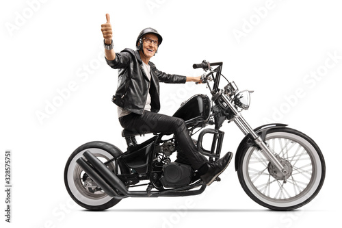 Cool mature biker in leather clothes riding a chopper and showing thumb up