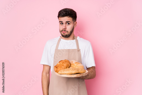 Young caucasian baker man isolated shrugs shoulders and open eyes confused.