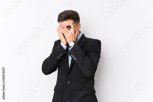 Young caucasian business man posing in a white background isolated Young caucasian business man blink through fingers frightened and nervous. © Asier