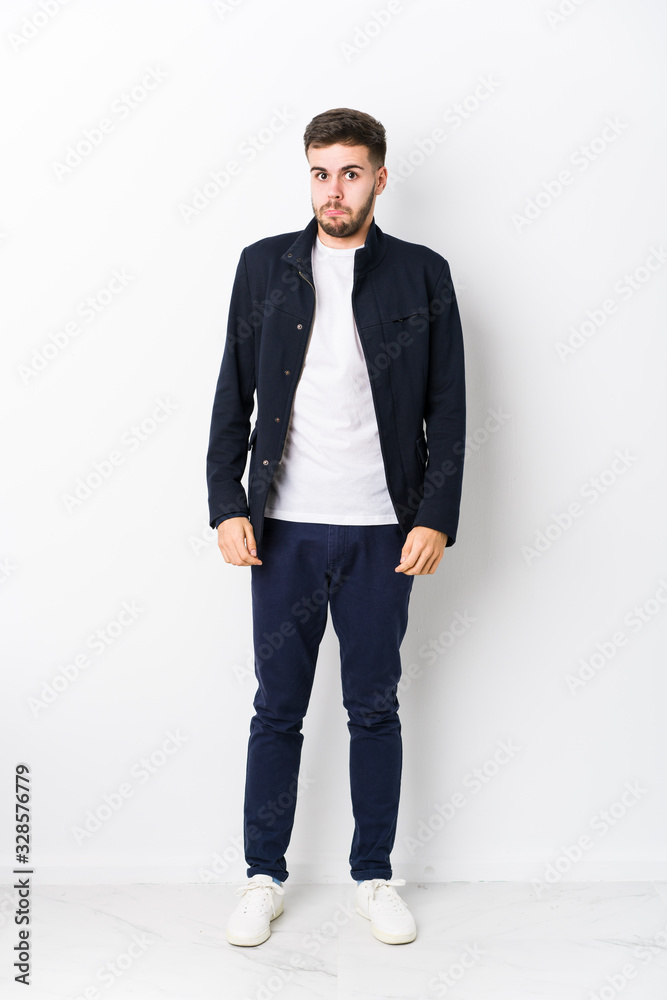 Full body young caucasian man isolated shrugs shoulders and open eyes confused. Full body young caucasian man isolated shrugs shoulders and open eyes confused.