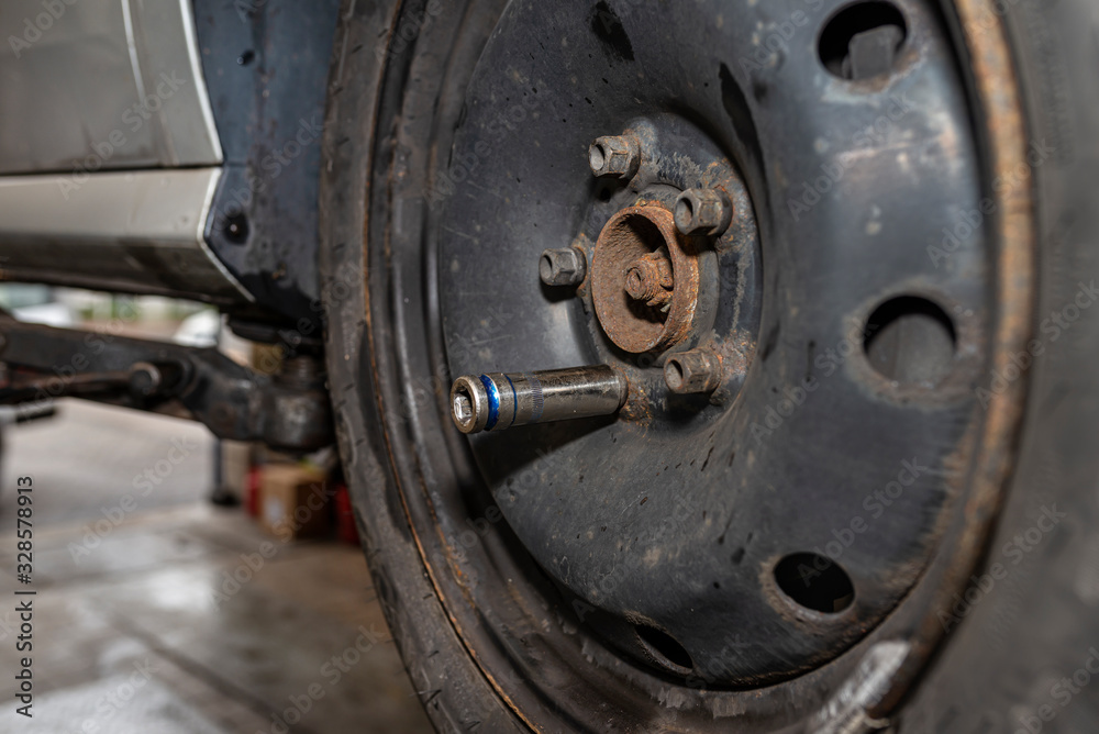 The pneumatic wrench cap attached to the screw on the steel car wheel after it has been replaced. The pneumatic wrench cap attached to the screw on the steel car wheel after it has been replaced.