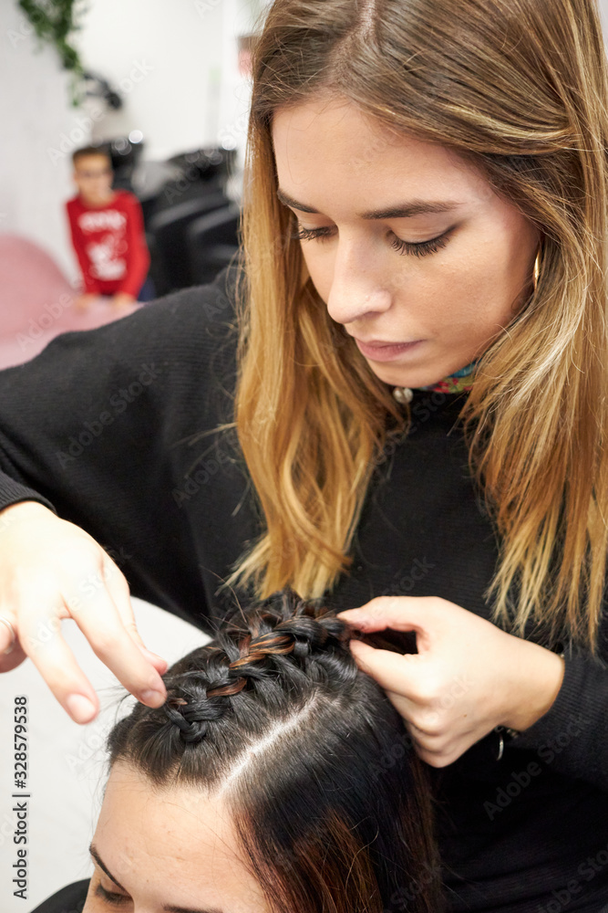 Fototapeta premium Hairdresser makes braid to client