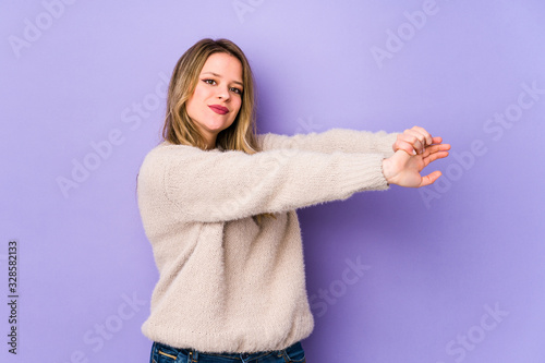 Young caucasian woman isolated on purple background stretching arms, relaxed position.