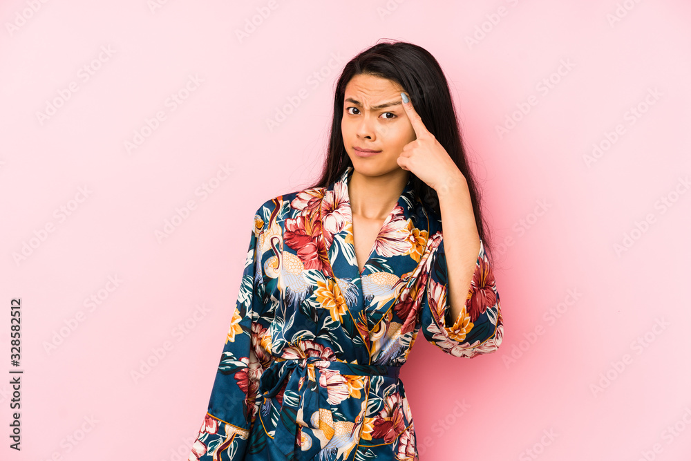 Young chinese woman wearing a asiatic pijama isolated pointing with finger at you as if inviting come closer. Young chinese woman wearing a asiatic pijama isolated pointing with finger at you as if inviting come closer.