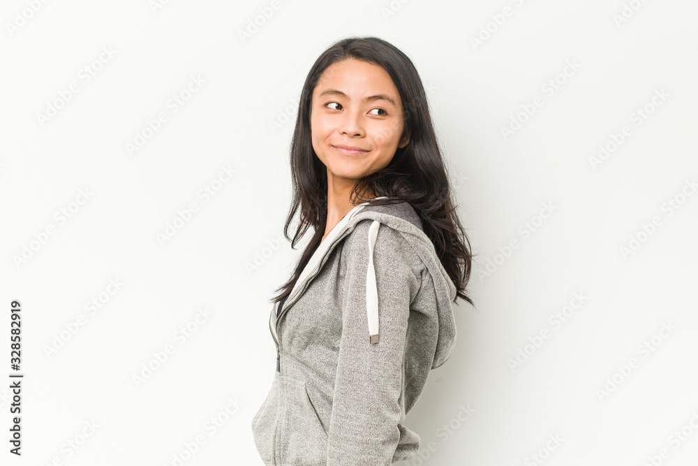Young fitness chinese woman looks aside smiling, cheerful and pleasant.
