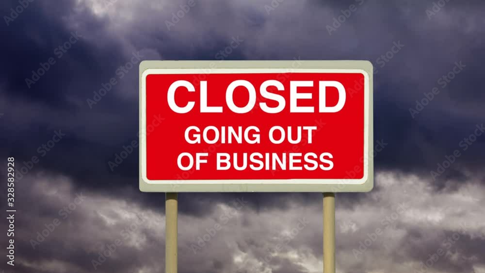 A closed red road sign warning of going out of business under a time lapse of gathering dark storm clouds. A closed red road sign warning of going out of business under a time lapse of gathering dark storm clouds.