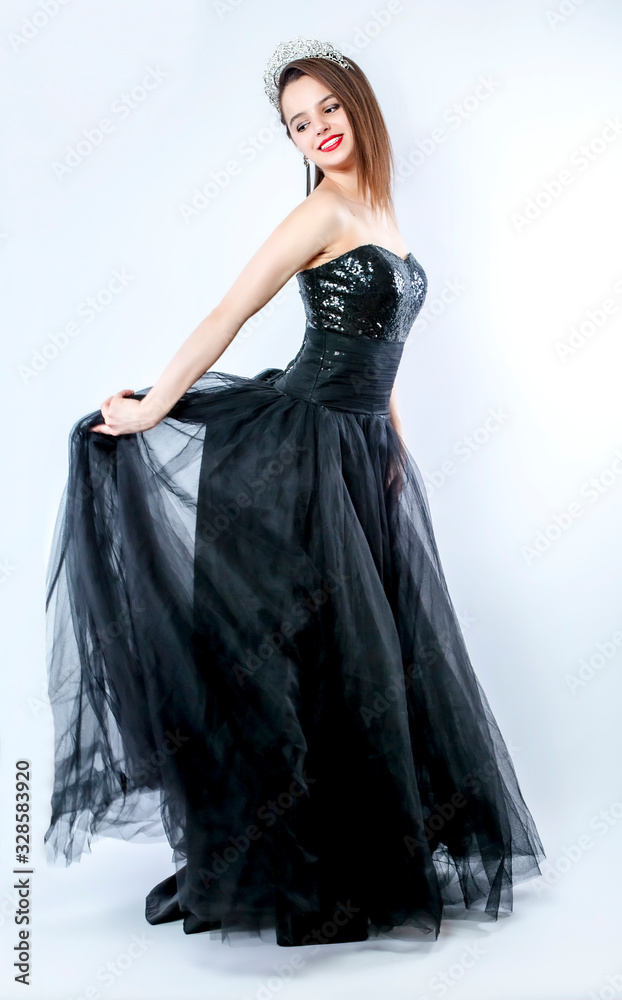The girl in a black puffy long and diamond diadem is dancing in the studio. Holds a long skirt with his hands. Isolated The girl in a black puffy long and diamond diadem is dancing in the studio. Holds a long skirt with his hands. Isolated