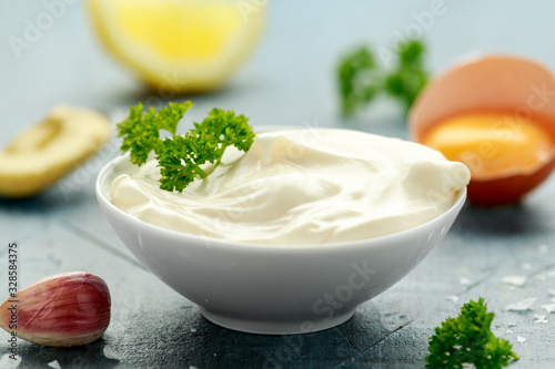Mayonnaise sauce in a white bowl with egg, mustard, garlic, lemon and herbs