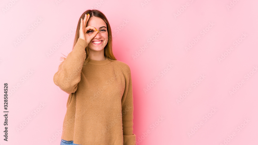Young caucasian woman isolated on pink background excited keeping ok gesture on eye. Young caucasian woman isolated on pink background excited keeping ok gesture on eye.