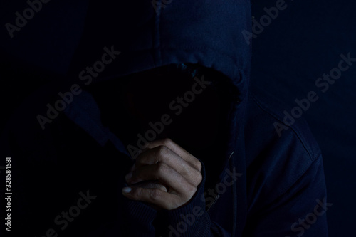 Young man worship and pray in cruch on dark black background. Christian faith or god concept. selective focus on finger