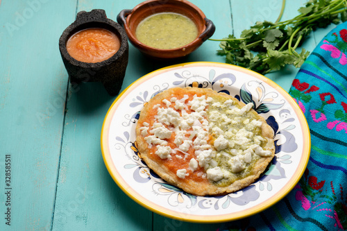 Mexican memela with green and red sauce on turqouise background