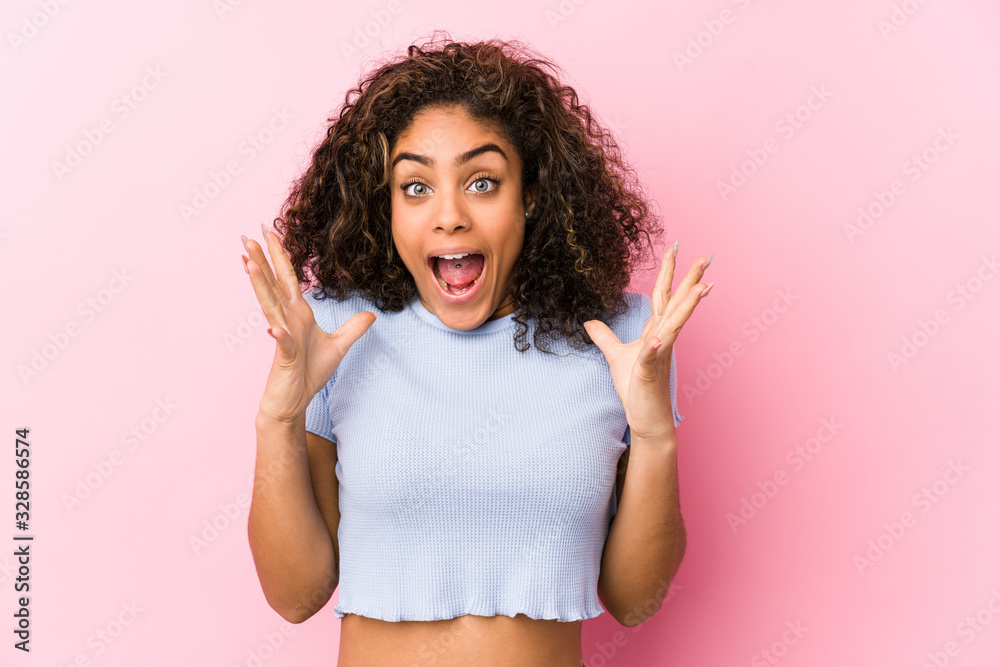 Young african american woman against a pink background celebrating a victory or success, he is surprised and shocked. Young african american woman against a pink background celebrating a victory or success, he is surprised and shocked.