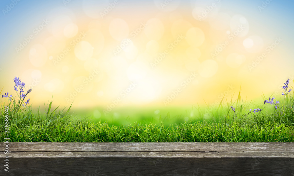 Naklejka A wooden table top product display with a fresh summer sunny blue sky with warm bokeh background with green grass meadow foreground.
