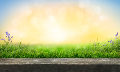A wooden table top product display with a fresh summer sunny blue sky with warm bokeh background with green grass meadow foreground.