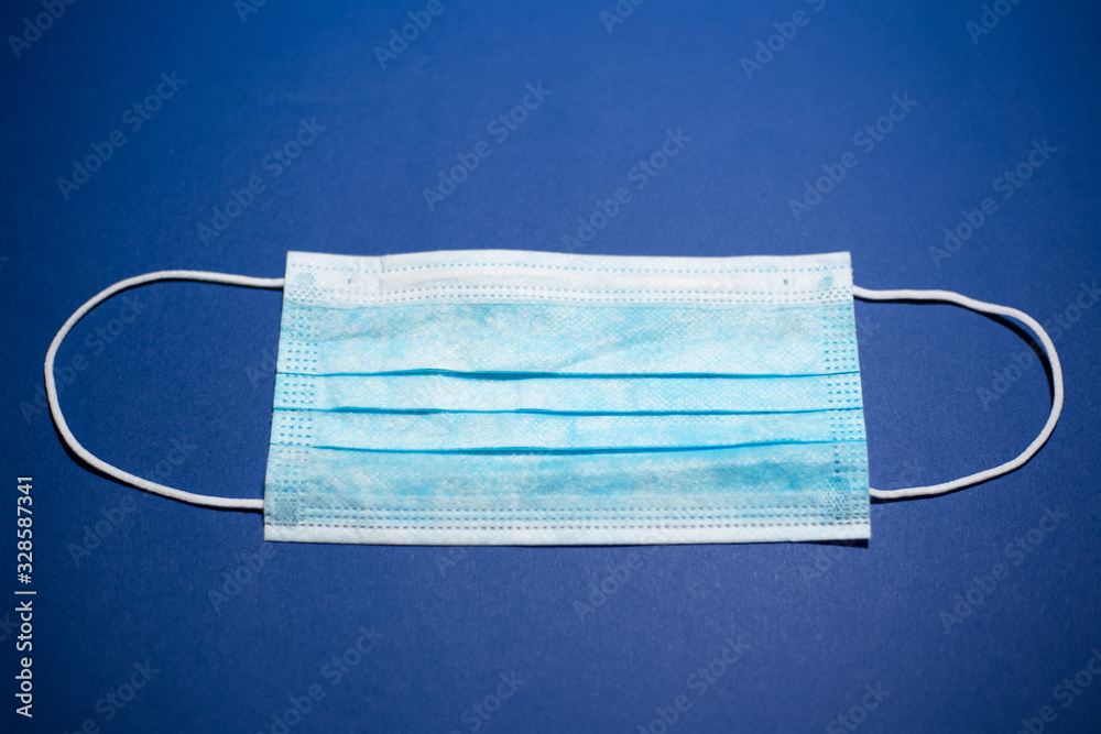 Close-up of medical flu mask, blue of color, on background of phantom blue color.