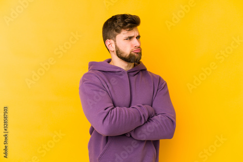 Young caucasian man isolated on yellow background suspicious, uncertain, examining you.