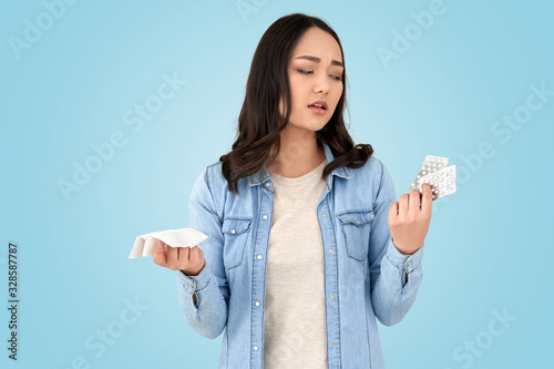 Young adult asian girl looking at pills in hands