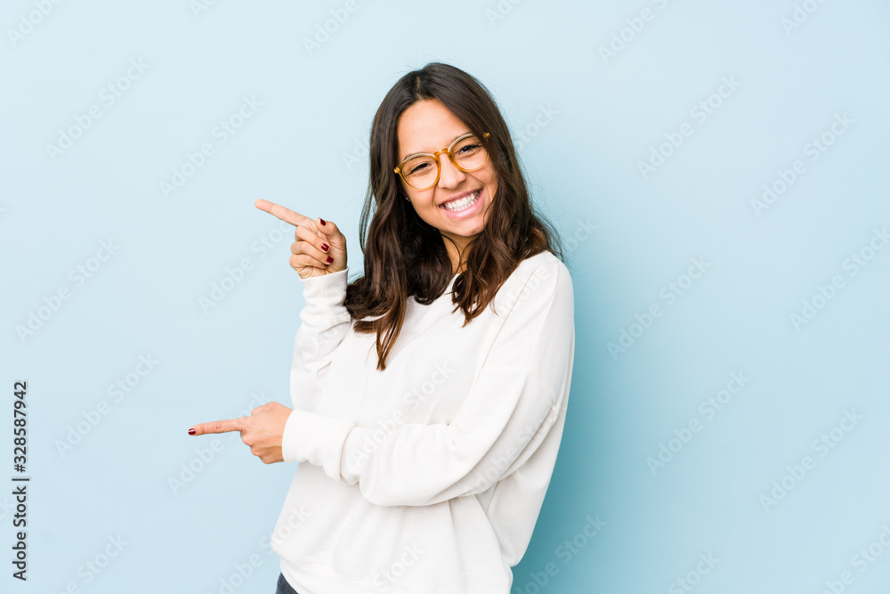 Young mixed race hispanic woman isolated pointing with forefingers to a copy space, expressing excitement and desire. Young mixed race hispanic woman isolated pointing with forefingers to a copy space, expressing excitement and desire.