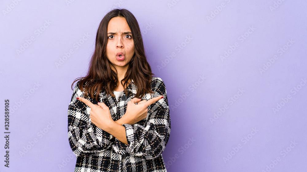 Young mixed race hispanic woman isolated points sideways, is trying to choose between two options. Young mixed race hispanic woman isolated points sideways, is trying to choose between two options.
