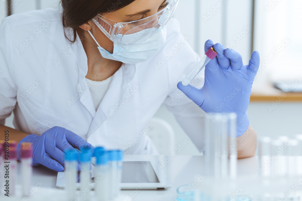 Close-up of professional female scientist in protective eyeglasses making experiment with reagents in laboratory. Medicine and research concept Close-up of professional female scientist in protective eyeglasses making experiment with reagents in laboratory. Medicine and research concept