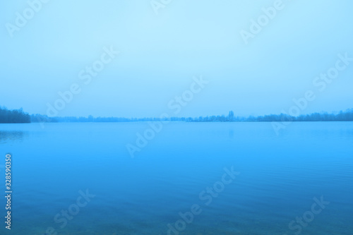 View of a dark lake in the fog. Cold evening
