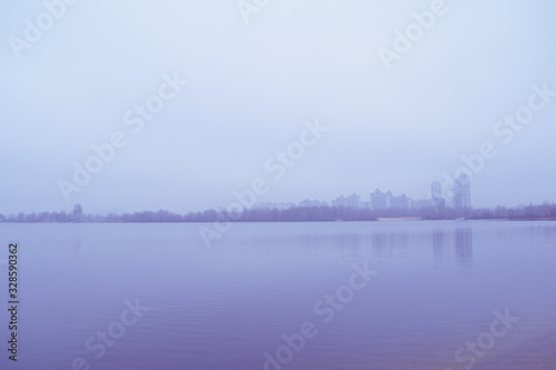 View across the lake in the fog on the city in the distance