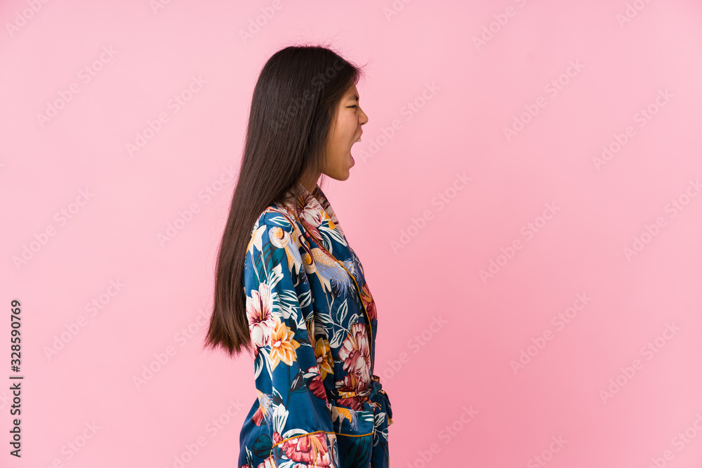 Young asian woman wearing a kimono pajamas shouting towards a copy space Young asian woman wearing a kimono pajamas shouting towards a copy space