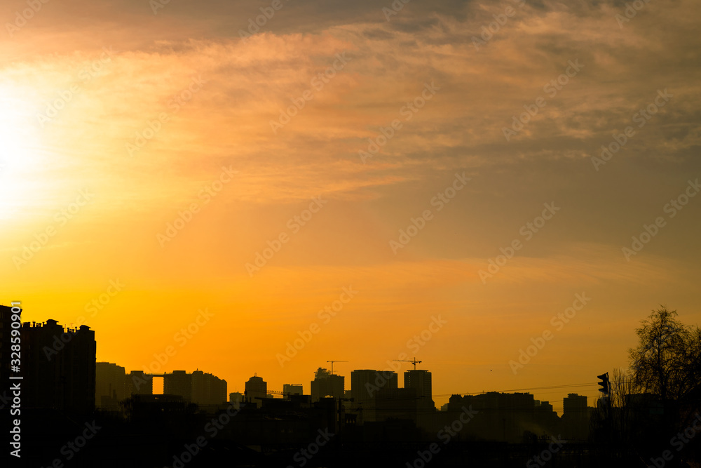 Dawn over the sleeping city. Black silhouettes of houses under the rising morning sun. Bright yellow sunrise