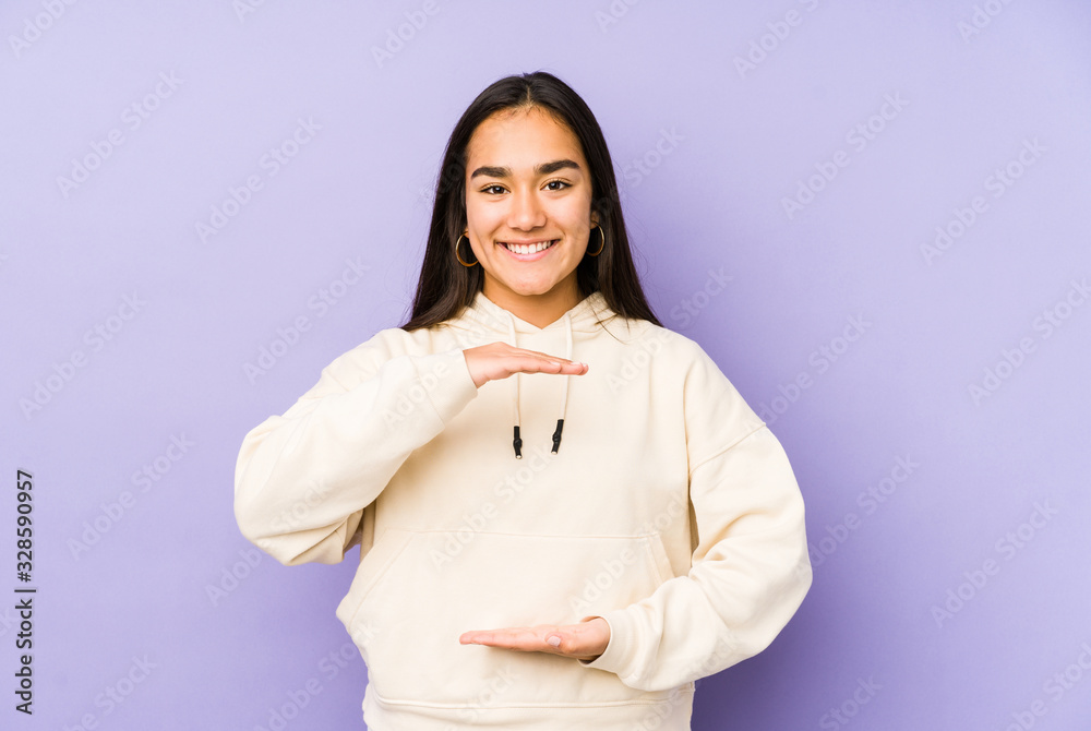 Young woman isolated on a purple background holding something with both hands, product presentation. Young woman isolated on a purple background holding something with both hands, product presentation.