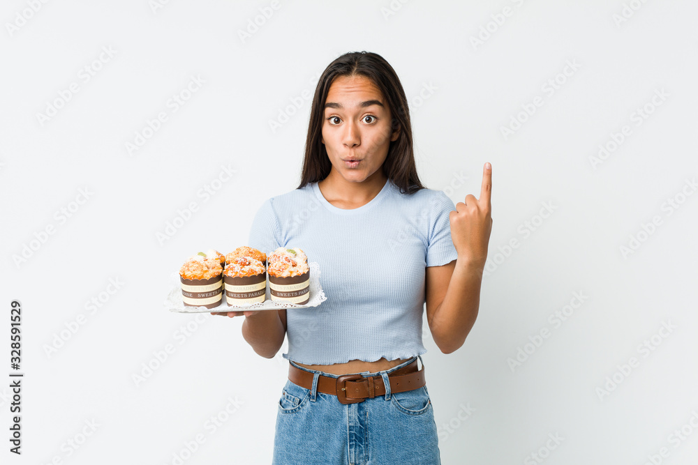 Young mixed race indian holding a sweet cakes having some great idea, concept of creativity. Young mixed race indian holding a sweet cakes having some great idea, concept of creativity.