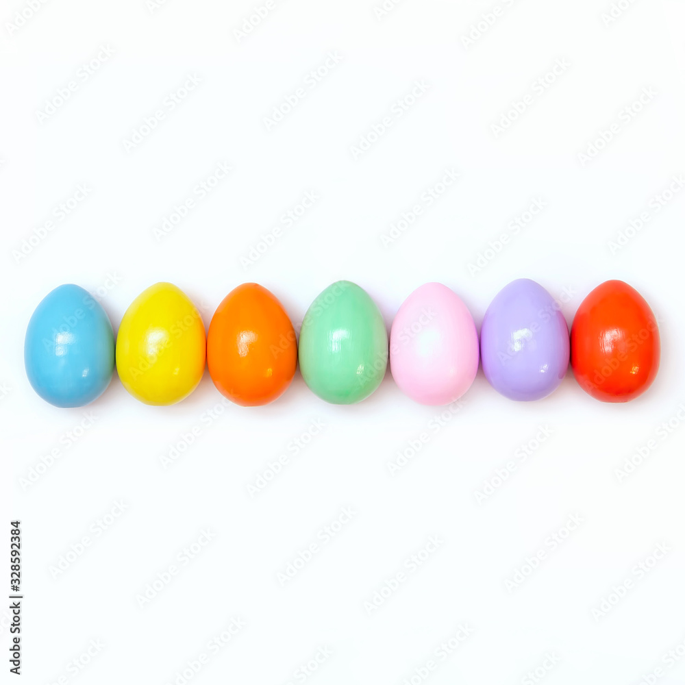 Top view of an Easter composition of painted eggs in bright juicy colors on a white background with a glossy texture. Holiday concept, flat layout, minimalism
