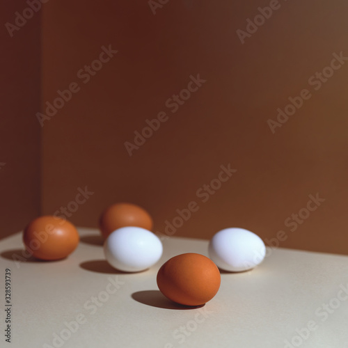 Five brown and white eggs with a hard shadow. They're in the corner of the box.