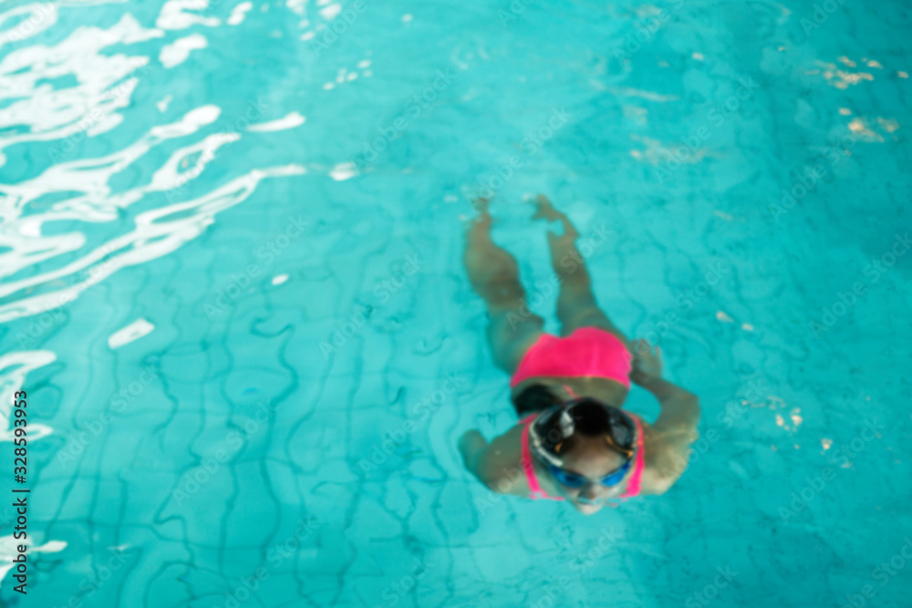 Blurred pool background Little girl swims underwater in the pool