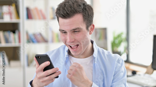Young Man Celebrating Success on Smartphone