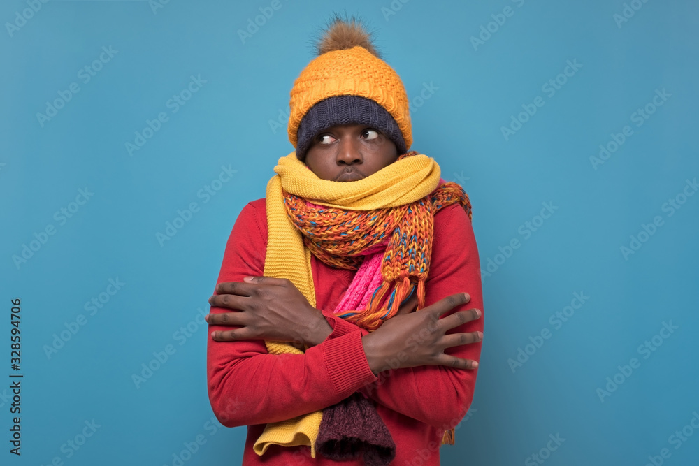 © Viktor Koldunov - african american funny man in several hats and scarfs on blue background.