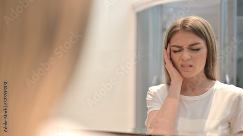 Woman Looking in Mirror and having Headache