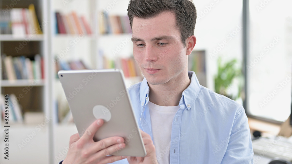 Cheerful Young Man using Tablet PC Cheerful Young Man using Tablet PC