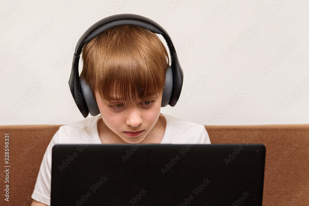 Teen in stereo headphones sitting with laptop. Computer games concept Teen in stereo headphones sitting with laptop. Computer games concept