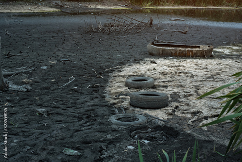 Garbage and old tires on the river Bank. Environmental contamination. Ecology concept