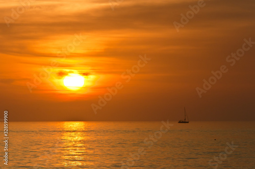 Front view, very far distance of a sailboat, motoring at sunseton calm waters of the gulf of Mexico © reve15