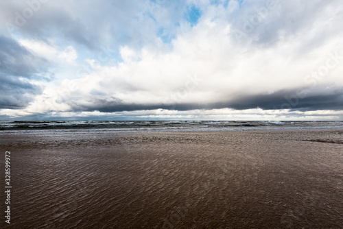 Storm clouds above the sea. Waves and water splashes. Warm evening sunlight. Baltic sea, Garciems, Latvia photo