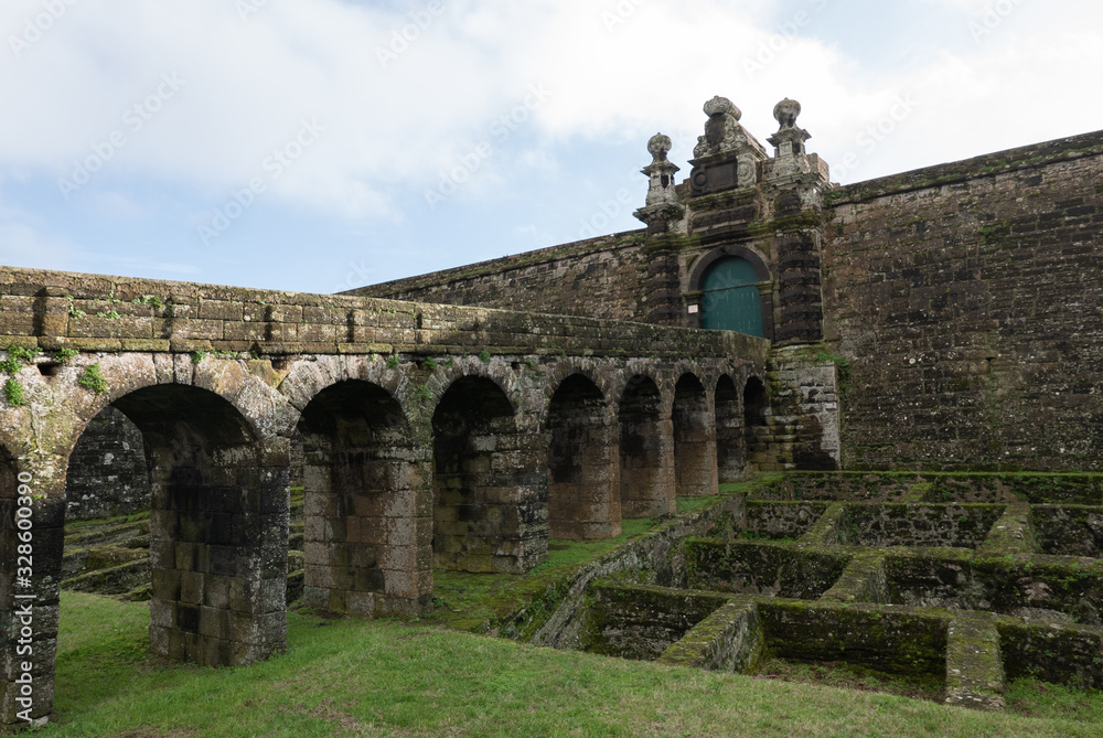 Entrance to old stone fortress with arches and blue door on Terceira Island