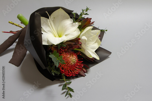 Close-up fresh bouquet of hippeastrum, leucospermum, leucodendron, eucalyptus on a gray background, selective focus photo